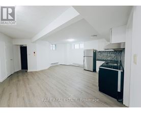 A spacious, empty room with a kitchenette and a dining area.