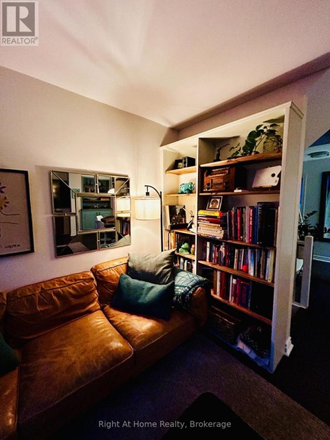 A living room with a brown leather couch and a bookshelf filled with books.