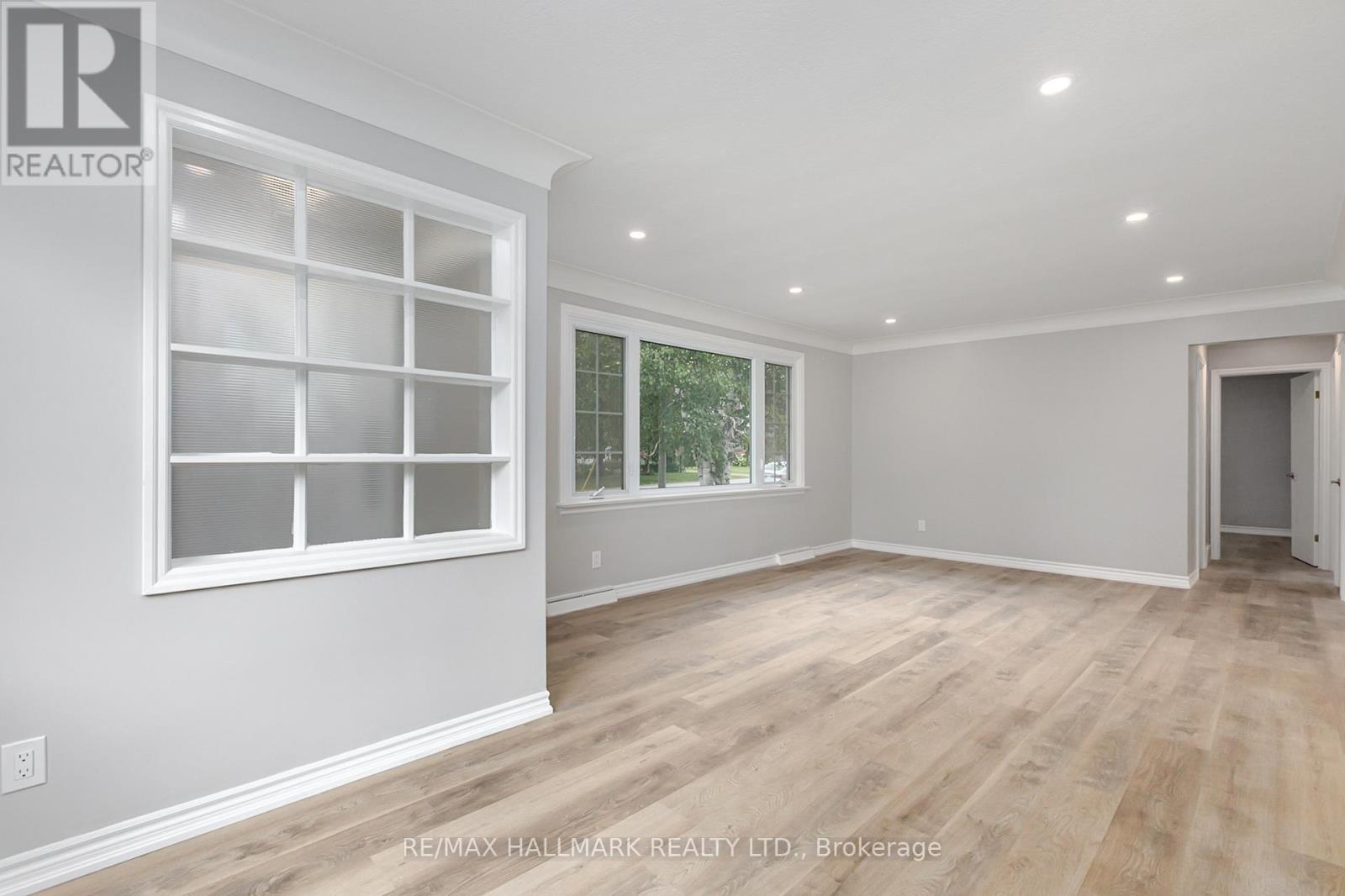 A spacious room with a large window and wooden flooring.
