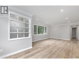 A spacious room with a large window and wooden flooring.