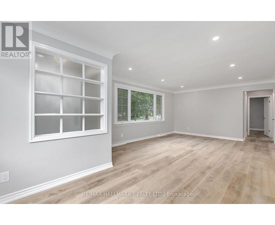 A spacious room with a large window and wooden flooring.