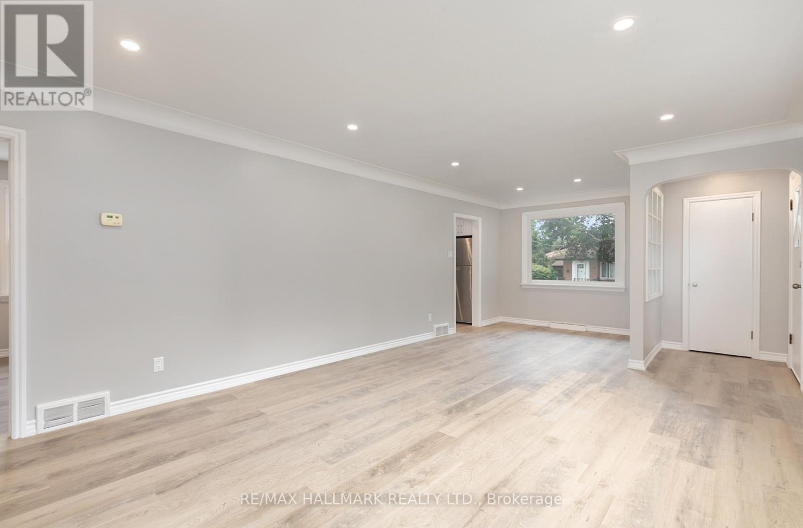 A spacious room with wooden flooring and white walls.