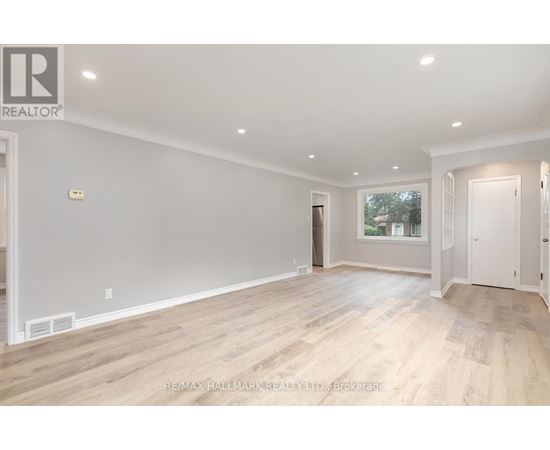 A spacious room with wooden flooring and white walls.