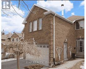 A brick house with a white garage door and a white pipe on the side.