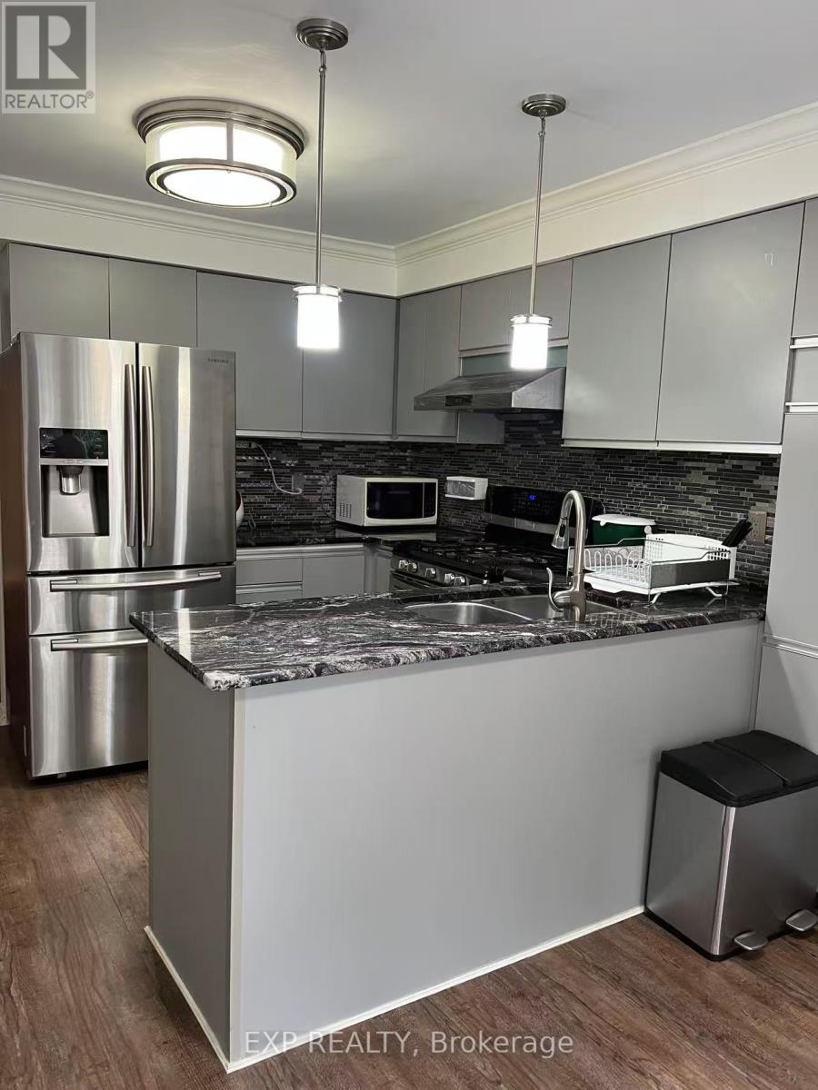 A kitchen with a refrigerator, microwave, and a countertop.