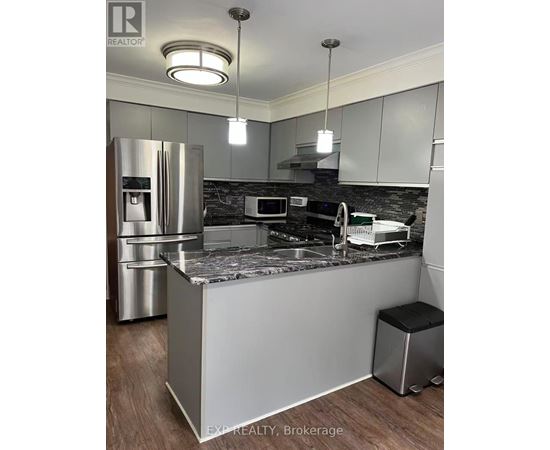 A kitchen with a refrigerator, microwave, and a countertop.