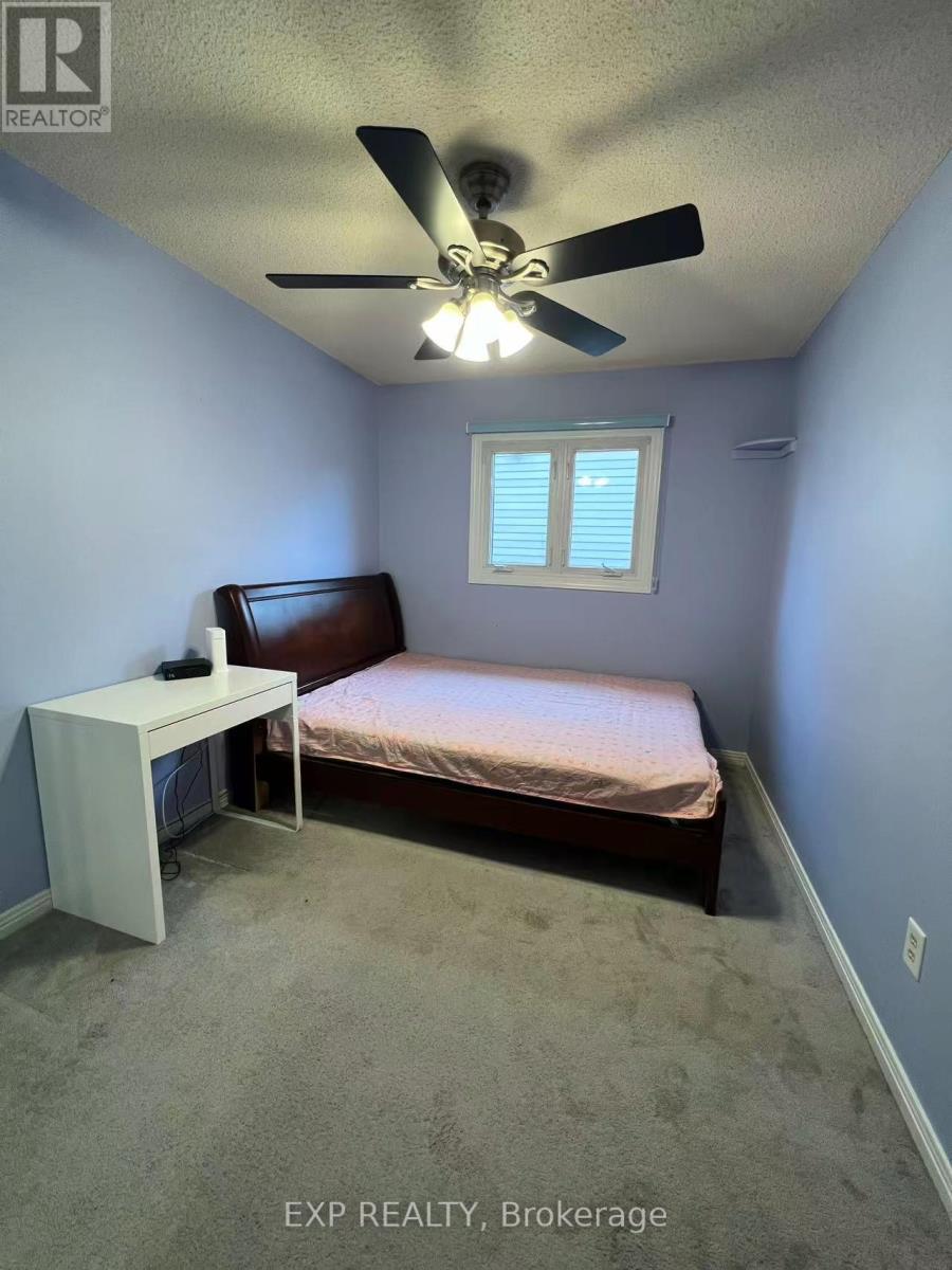A bedroom with a bed, a fan, and a window.