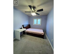 A bedroom with a bed, a fan, and a window.