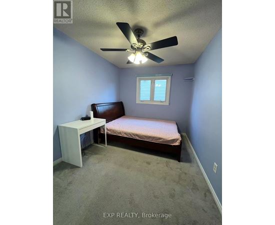 A bedroom with a bed, a fan, and a window.