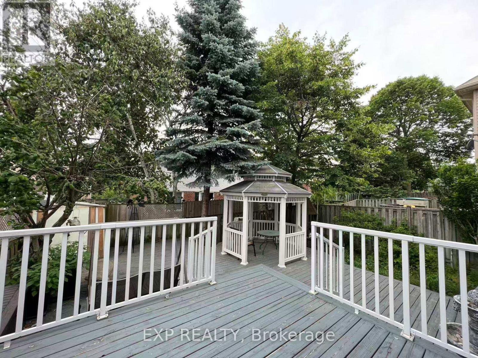 A wooden deck with a gazebo and white railing.