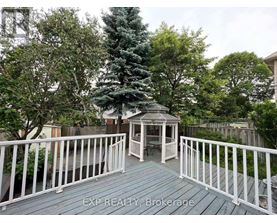 A wooden deck with a gazebo and white railing.
