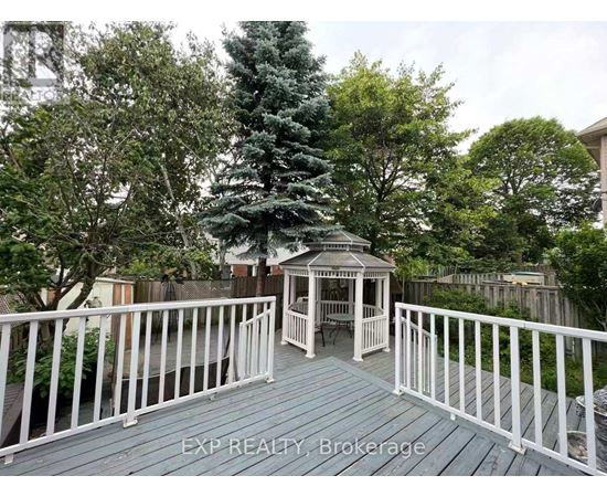 A wooden deck with a gazebo and white railing.
