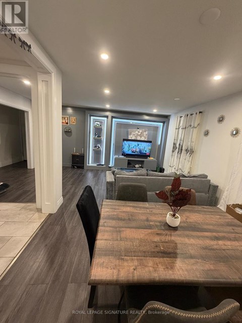 A living room with a wooden table and a television on the wall.