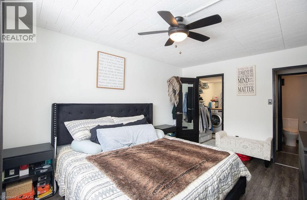 A bedroom with a bed, a fan, and a dresser with a mirror.