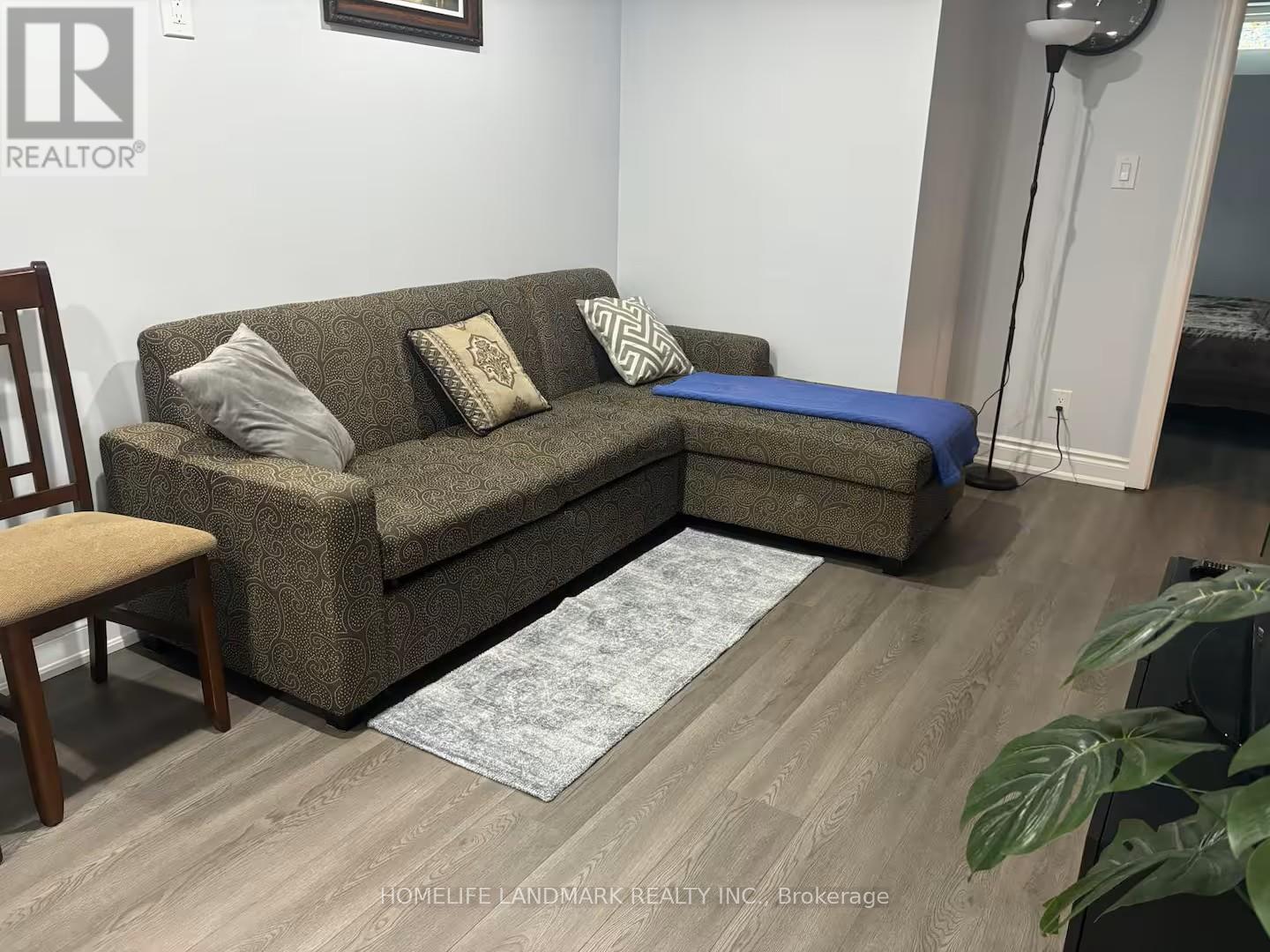 A living room with a brown couch and a grey rug.