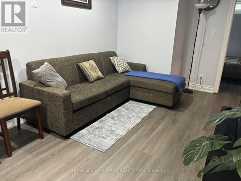 A living room with a brown couch and a grey rug.