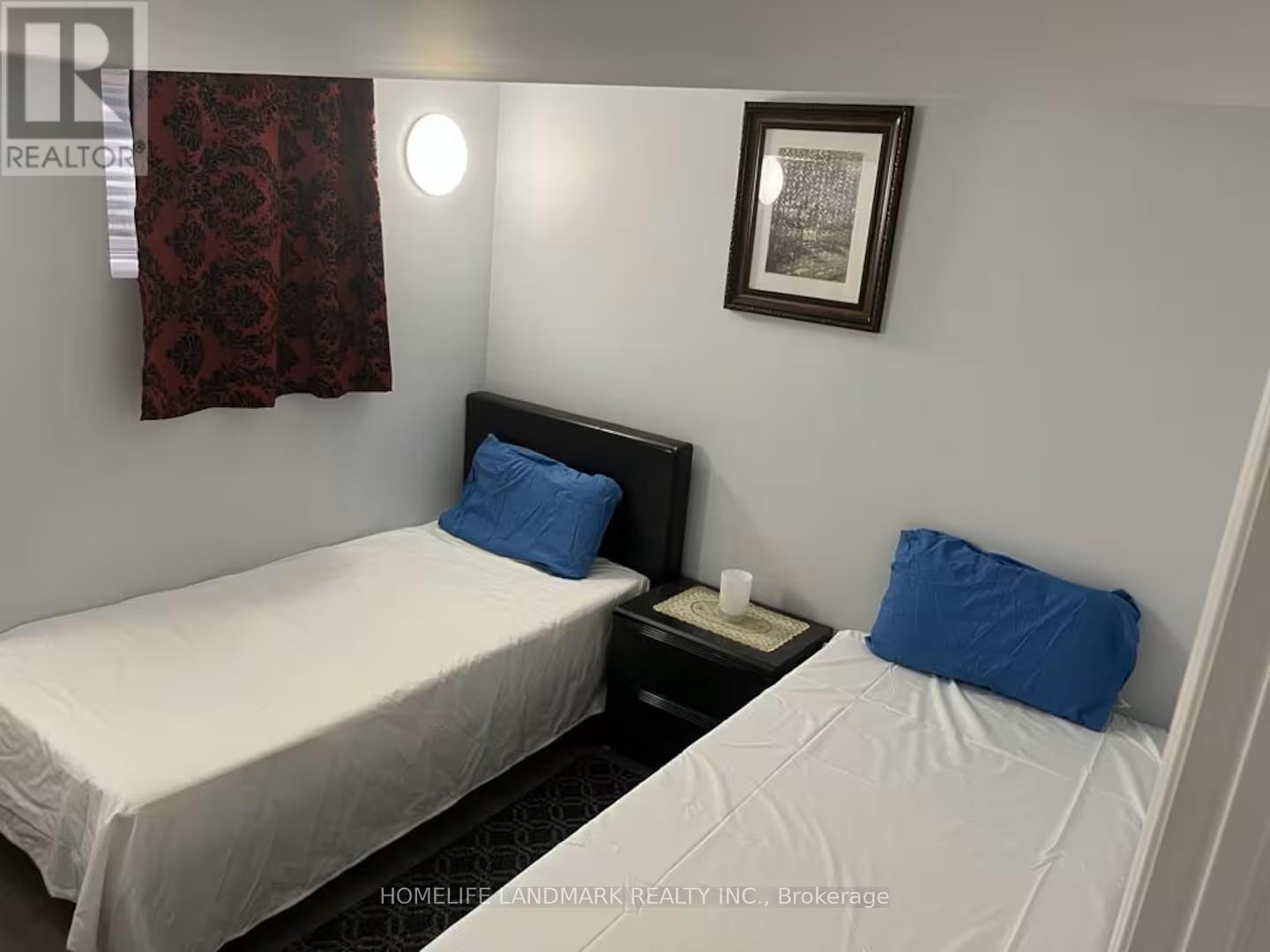 A bedroom with two beds, one with a blue pillow.