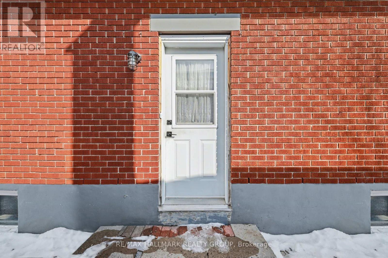 A red brick house with a white door and a small window above it.