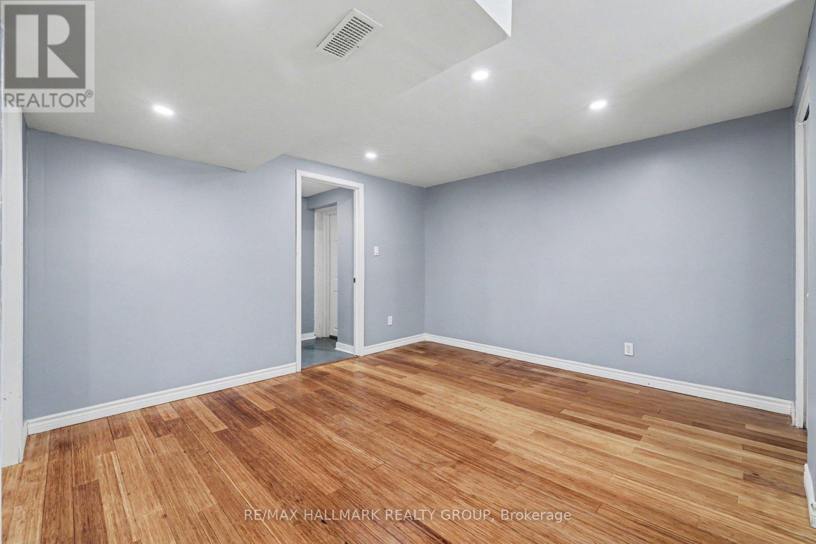 A spacious room with wooden flooring and a white door.