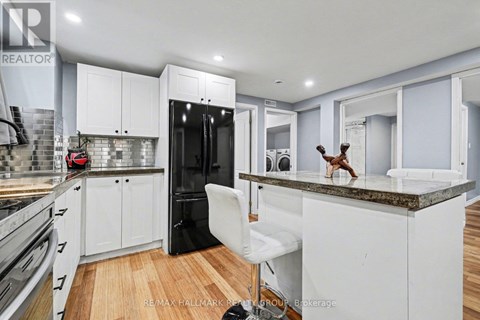A kitchen with white cabinets and a black fridge.