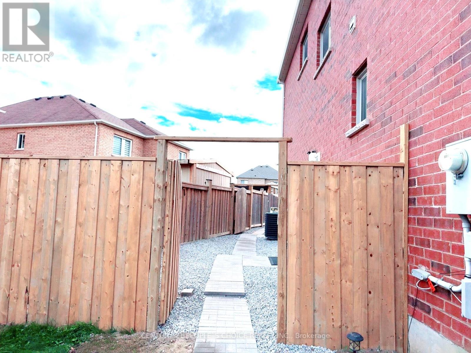 A wooden fence with a gate is in front of a brick building.