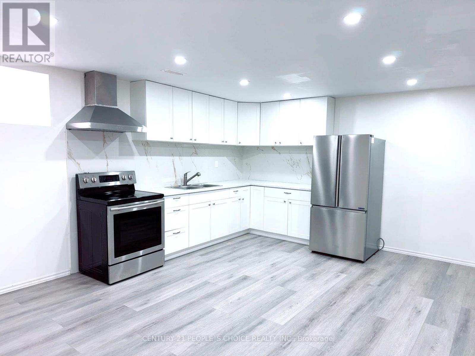 A modern kitchen with a stainless steel refrigerator and a black stove top oven.