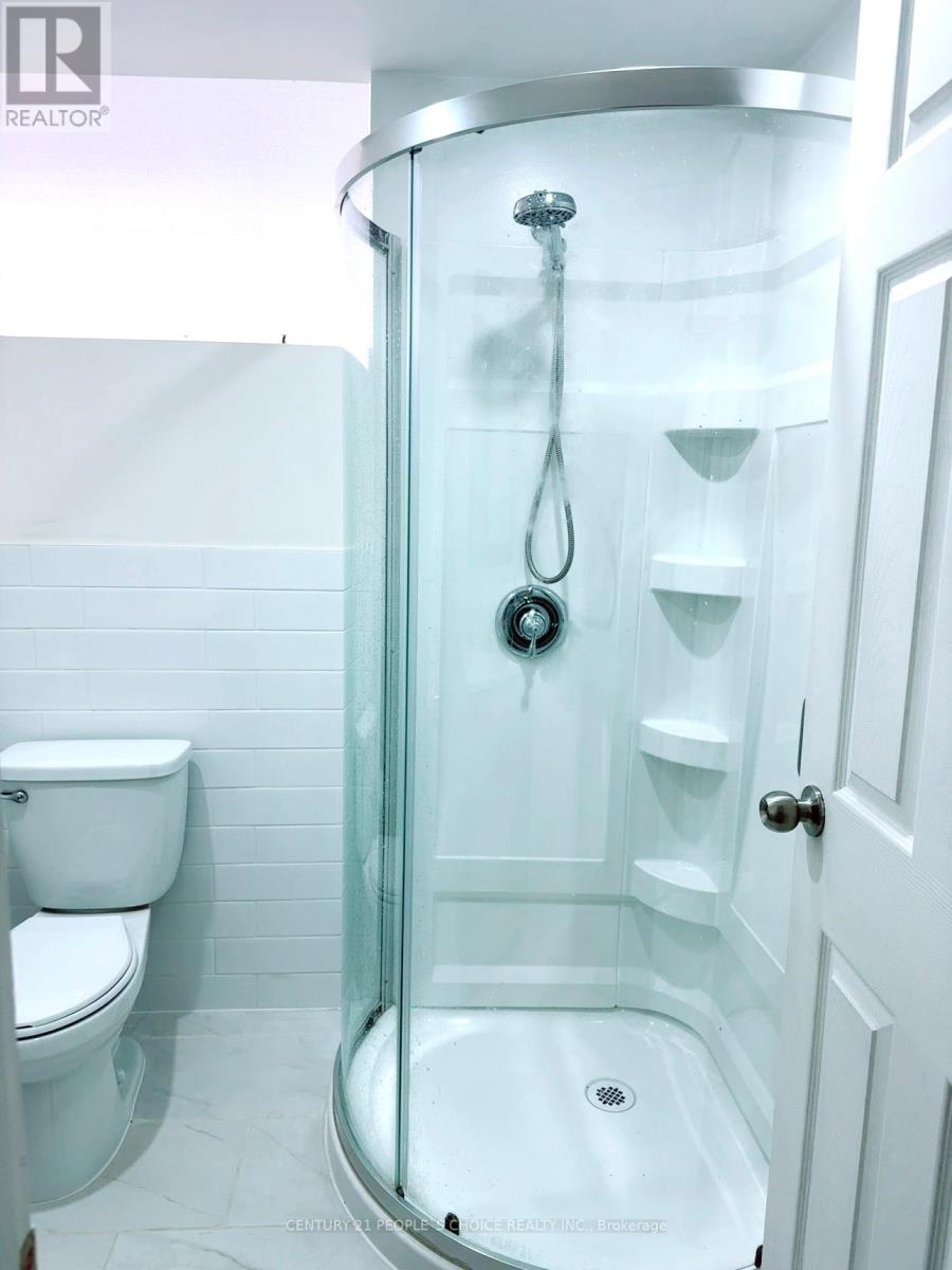 A white bathroom with a glass shower stall and a toilet.