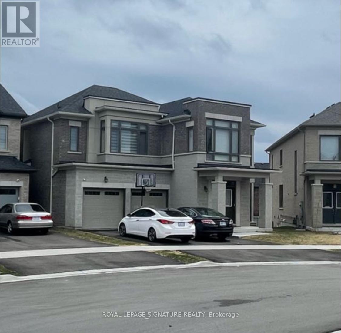 A white car is parked in front of a grey house.