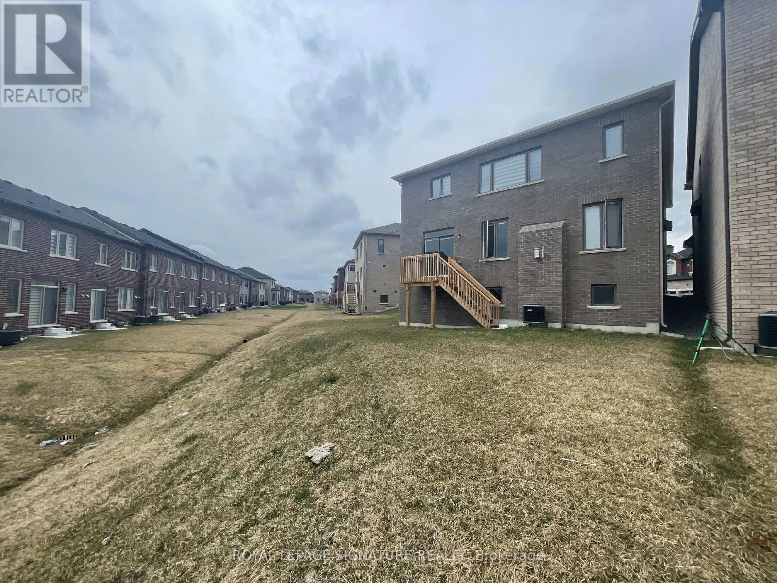 A grassy area in front of apartment buildings with a REALTOR® logo.