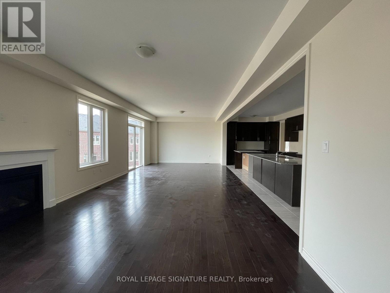 A spacious room with a fireplace and wood flooring.