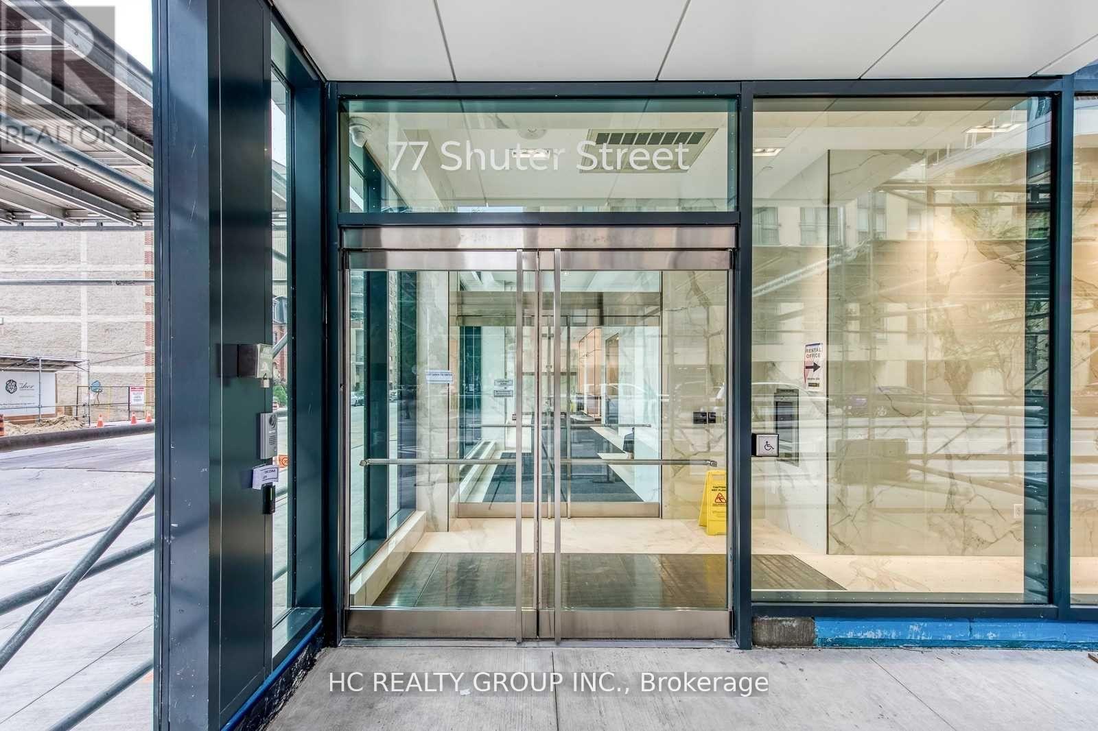 The entrance to a building with a glass door and a sign that reads "77 Shuter Street".