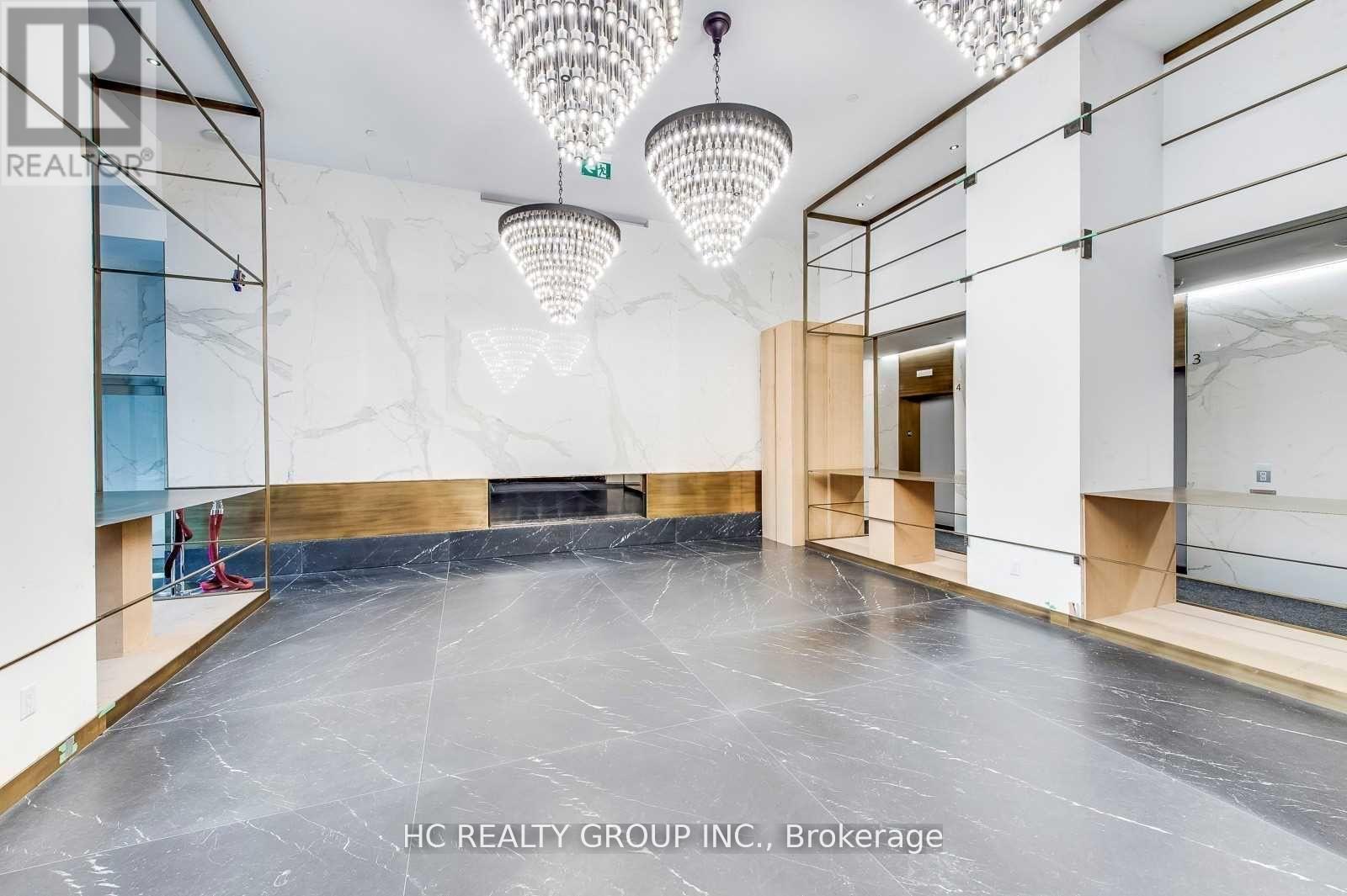 A spacious room with a grey floor and a white ceiling with chandeliers.