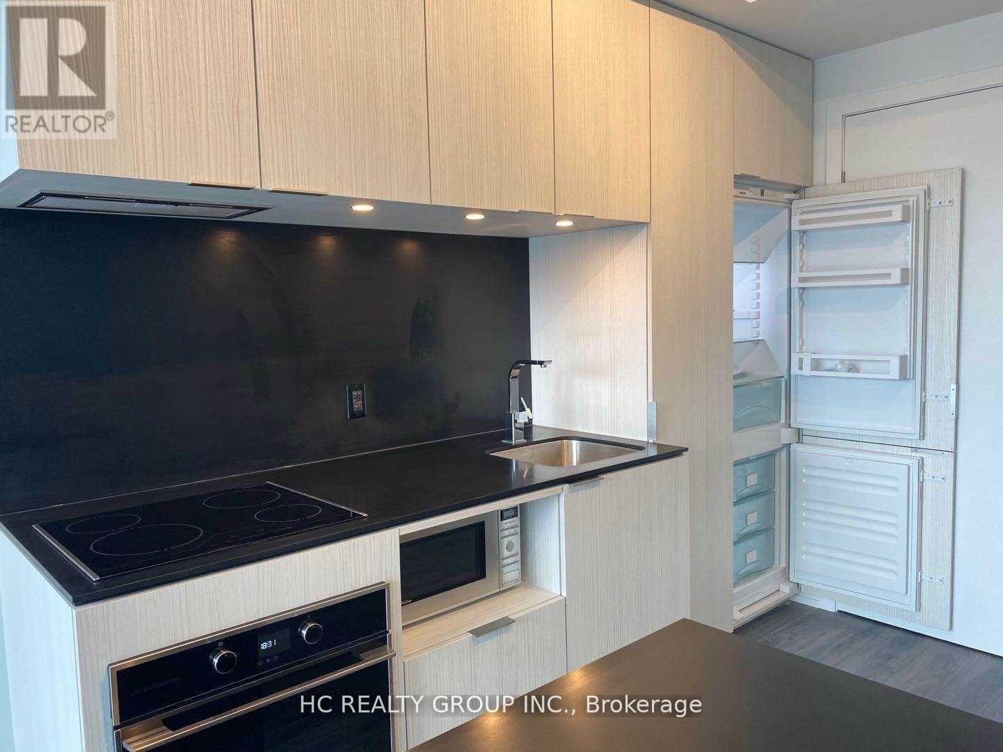 A modern kitchen with wooden cabinets and black countertops.