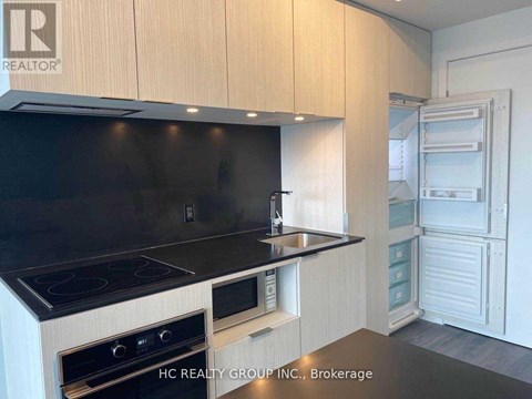 A modern kitchen with wooden cabinets and black countertops.