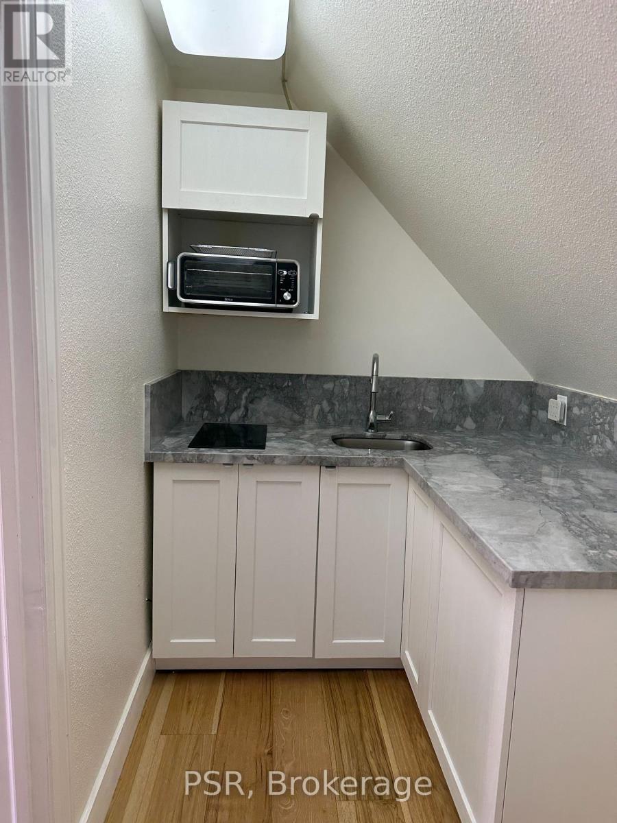 A kitchen with white cabinets and a marble countertop.