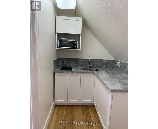 A kitchen with white cabinets and a marble countertop.