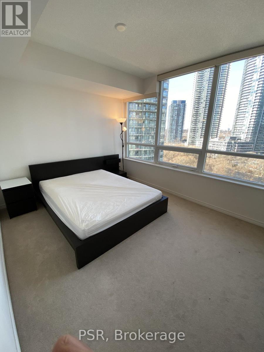 A bedroom with a large bed and a window overlooking a cityscape.