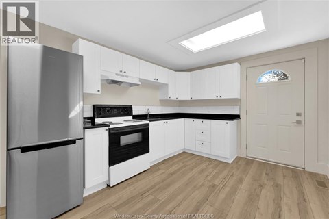 A kitchen with white cabinets and a stainless steel refrigerator.