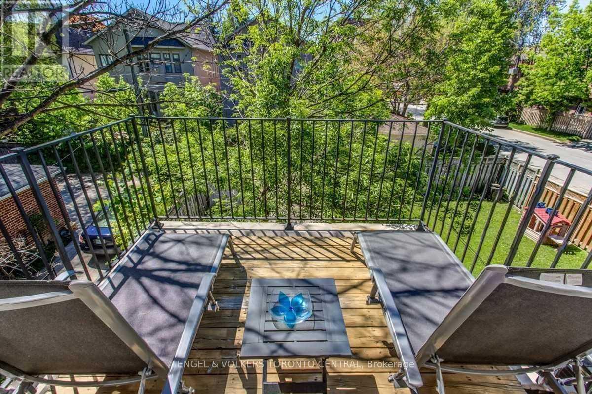A deck with a hot tub and chairs overlooks a green yard.