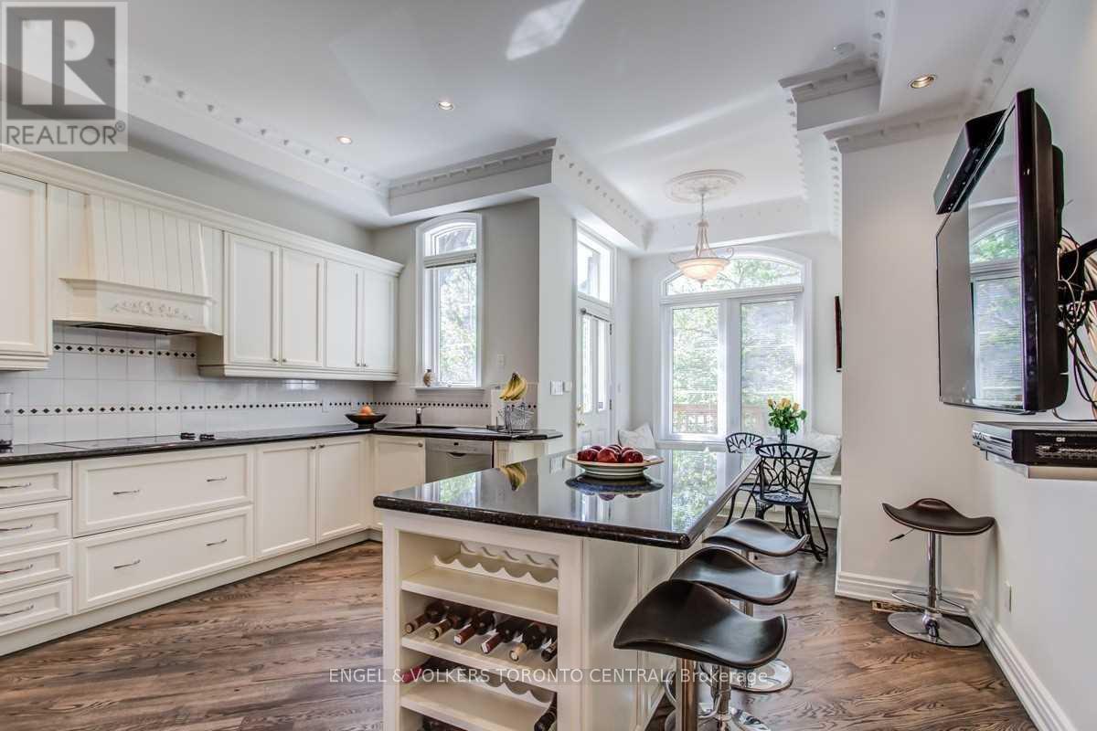 A kitchen with white cabinets and a black island.