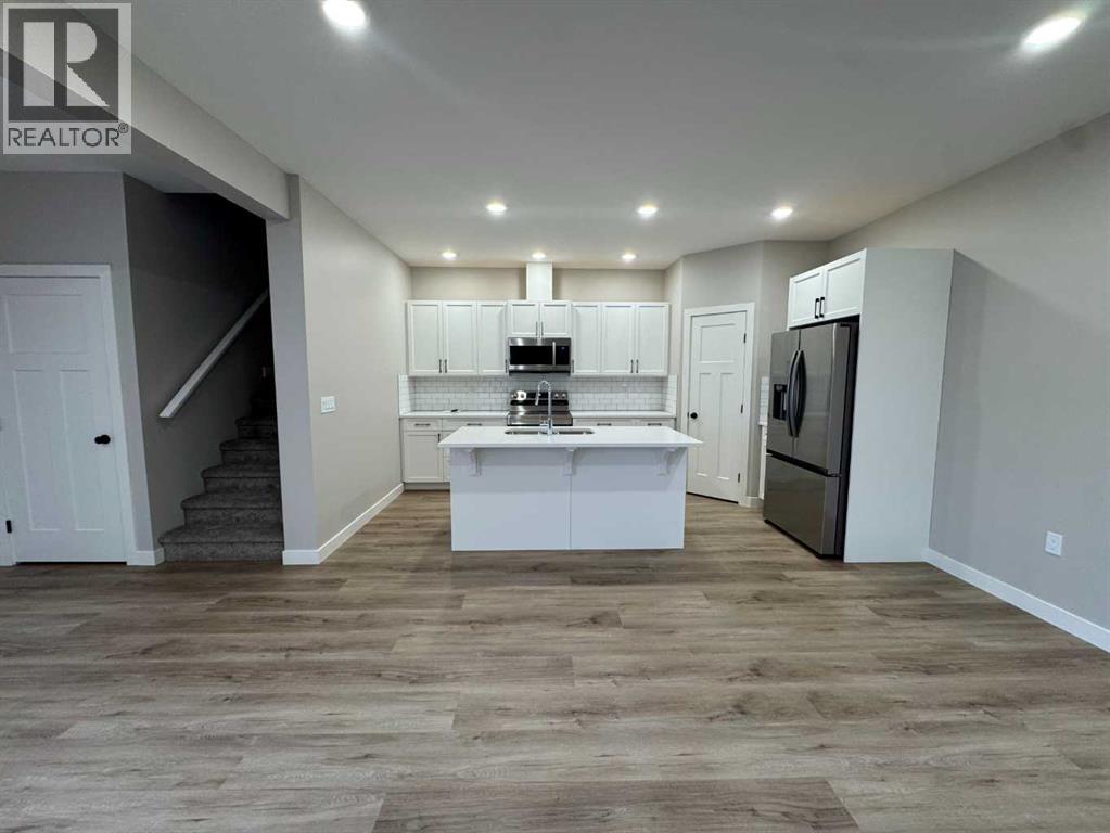 A well-lit kitchen with a refrigerator, sink, and cabinets.