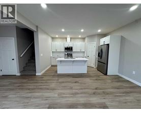 A well-lit kitchen with a refrigerator, sink, and cabinets.