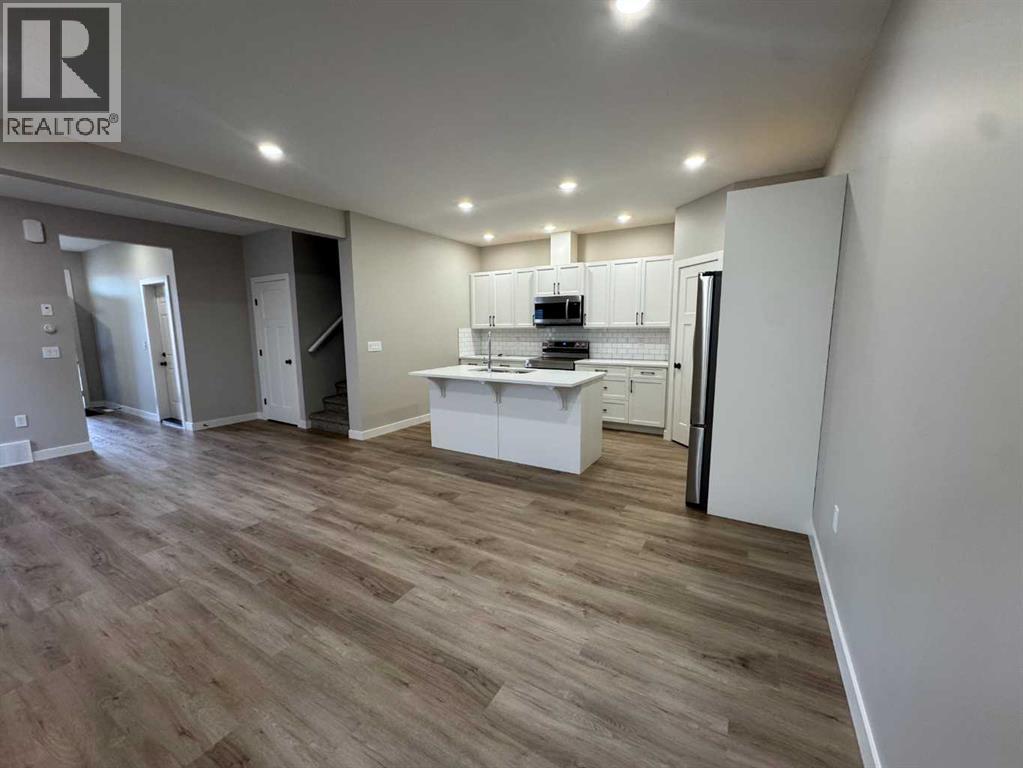 A well-lit, spacious kitchen area with wooden flooring and white cabinetry.