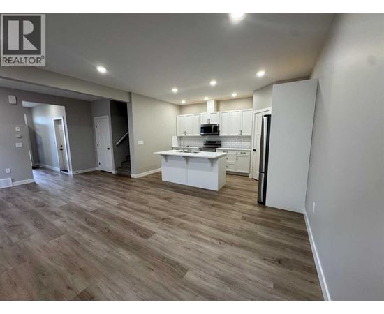 A well-lit, spacious kitchen area with wooden flooring and white cabinetry.
