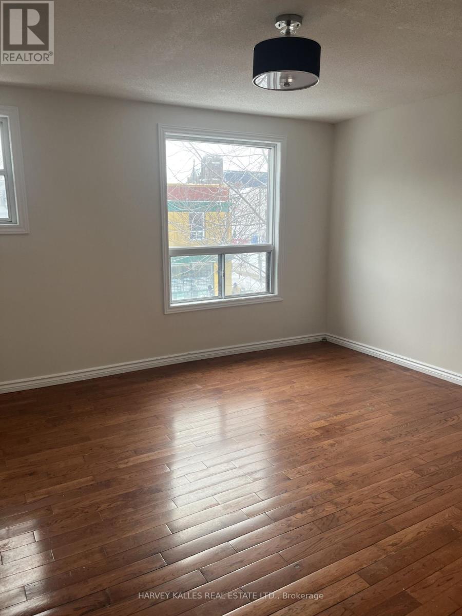 A room with wooden flooring and a window showing a view of a building outside.