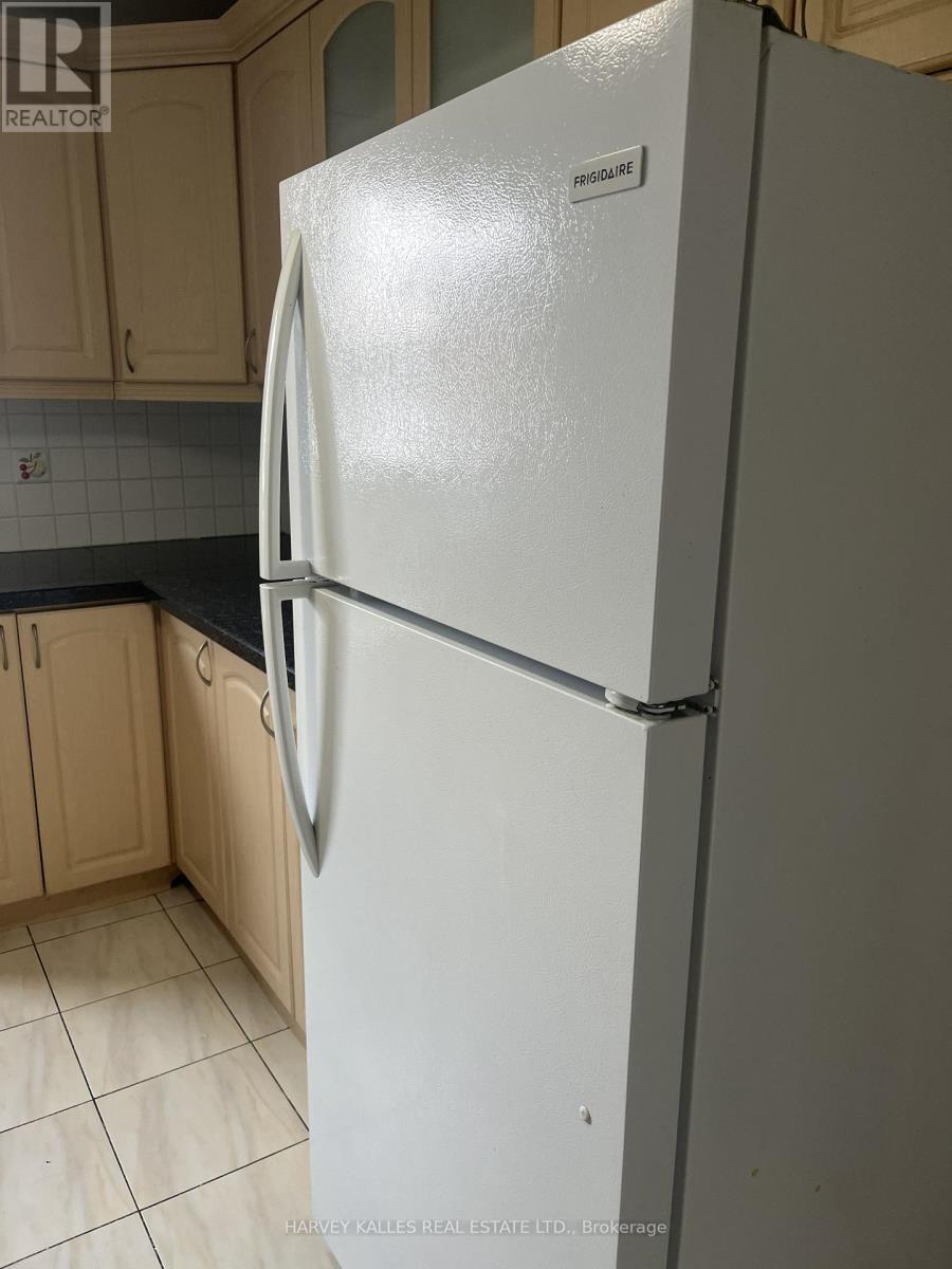 A white fridge in a kitchen with wooden cabinets.