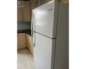 A white fridge in a kitchen with wooden cabinets.