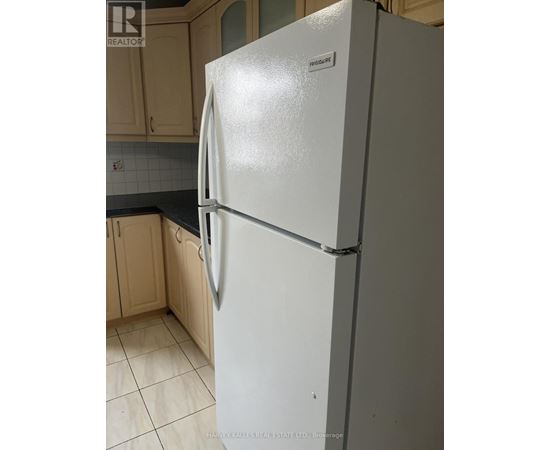 A white fridge in a kitchen with wooden cabinets.
