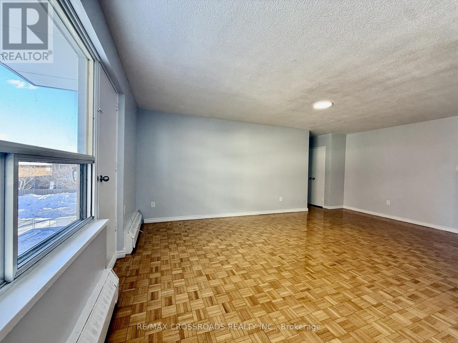A room with wooden flooring and a window showing a snowy scene outside.