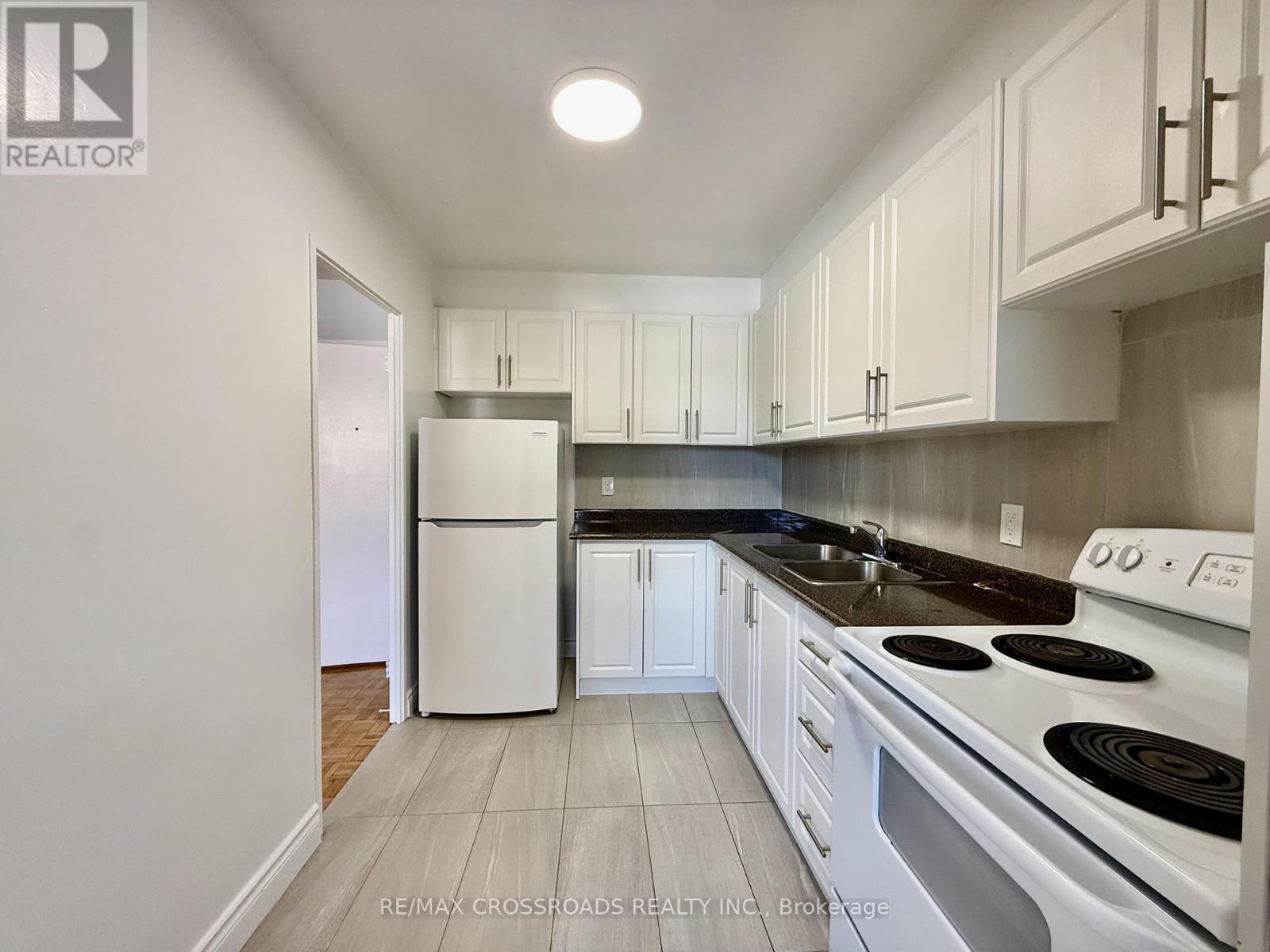 A kitchen with white cabinets and a white fridge.